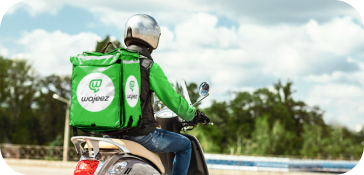 Un livreur sur un scooter vert avec un caisson de livraison Wajeez à l'arrière.