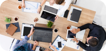 Des gens travaillant sur des ordinateurs portables autour d'une table, collaborant et se concentrant sur leurs tâches.